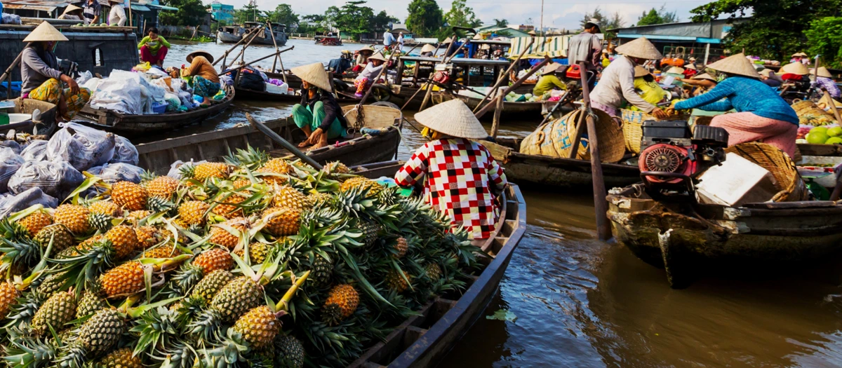 Floating market boats piled with fruit on Thailand, Cambodia and Vietnam student tours.