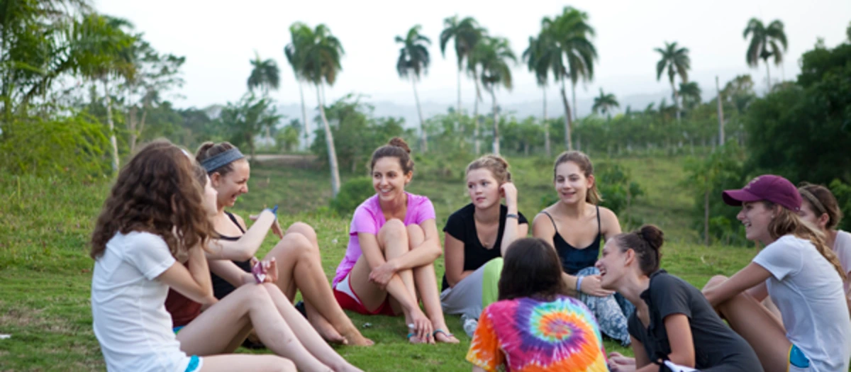 Students gathered on grass among palm trees on an environmental leadership student tour.