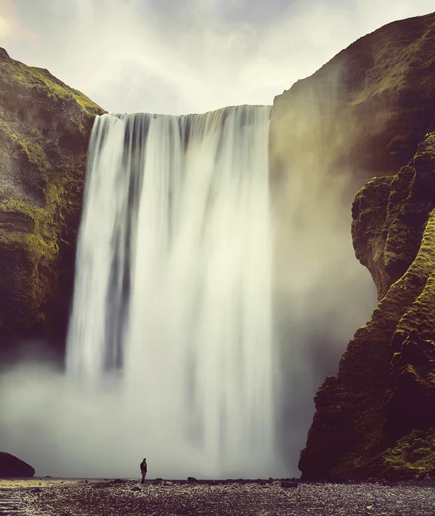Large waterfall with person standing at the base on EF Iceland educational tour.
