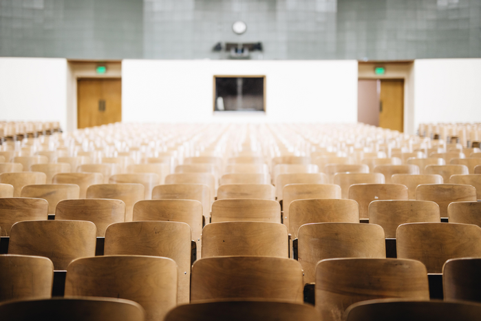 empty lecture hall with wooden chairs by Nathan Dumlao via Unsplash