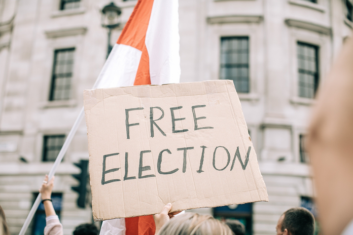 cardboard sign being held up that says \"Free Election\"