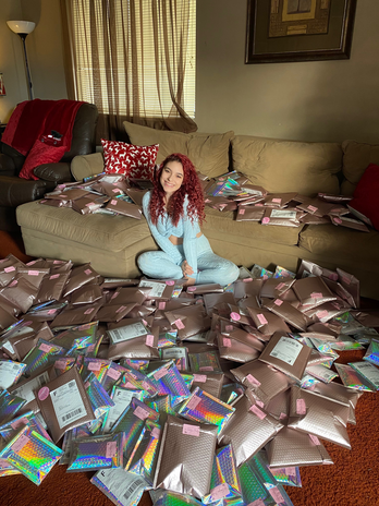 Girl with red hair sits on the ground in a living room surrounded by packages