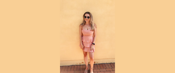 girl in pink dress in front of orange wall