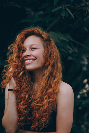 woman with red hair smiling by Tomaz Barcellos