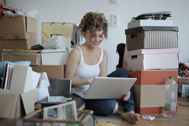 woman sitting on the floor among some boxes in a messy room