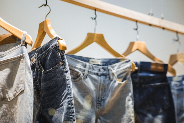 jeans on clothing rack by Jason Leung