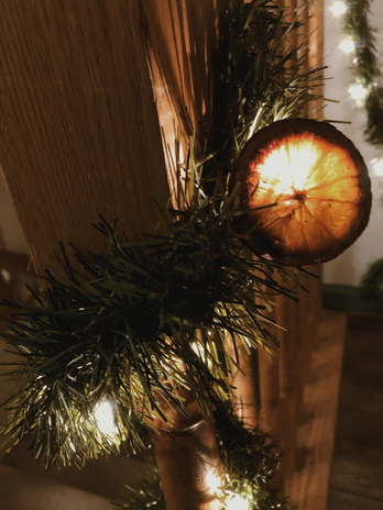 Orange Christmas garland strung around staircase with lights that illiumate the garland