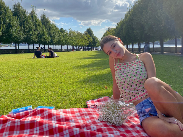 Sofia sitting in a park on a red and white checkerboard blanket