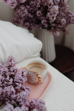 lilacs and coffee on bed by Ionana Motoc