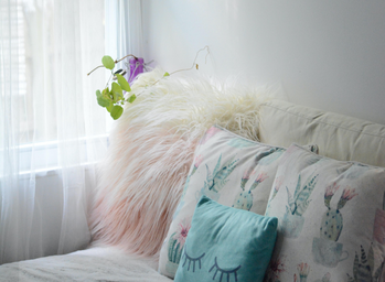pink and white fluffy pillows on a white bed