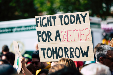 cardboard sign being held up that says “Fight Today For A Better Tomorrow”
