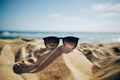 raybans glasses sitting on top sand
