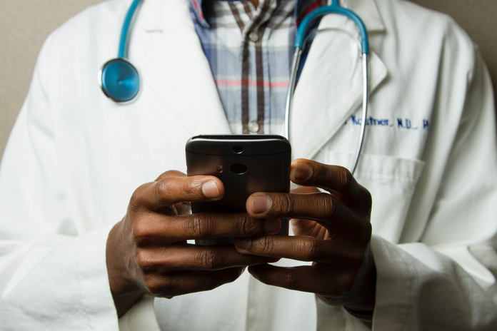Doctor holding a cell phone by National Cancer Institute via Unsplash