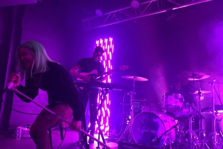 woman on stage performing with purple background