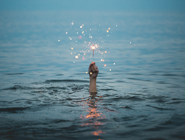 person in water holding a sparkler
