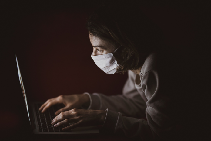Woman with mask on laptop