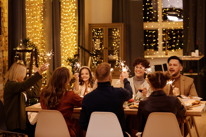 A family sits around a festive dinner table with sparklers.