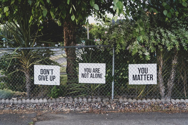 Don\'t give up signs in a fence