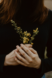 woman in black shirt holding yellow flowers