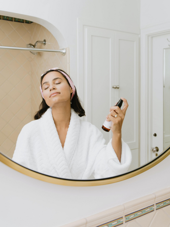 woman in white robe holding skincare product by Kalos Skincare on Unsplash