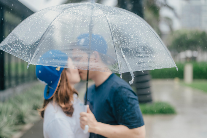 A couple kisses under an umbrella by Do Linh