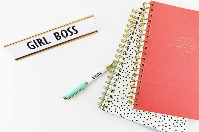desk with notebooks and "girl boss" plaque on it