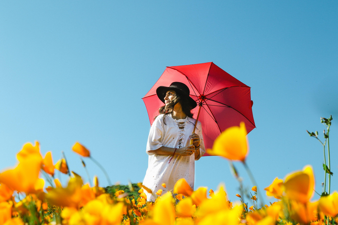 white dress with a red umbrella in a flower field