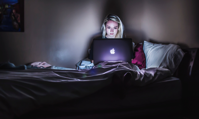 Woman sitting in bed using laptop