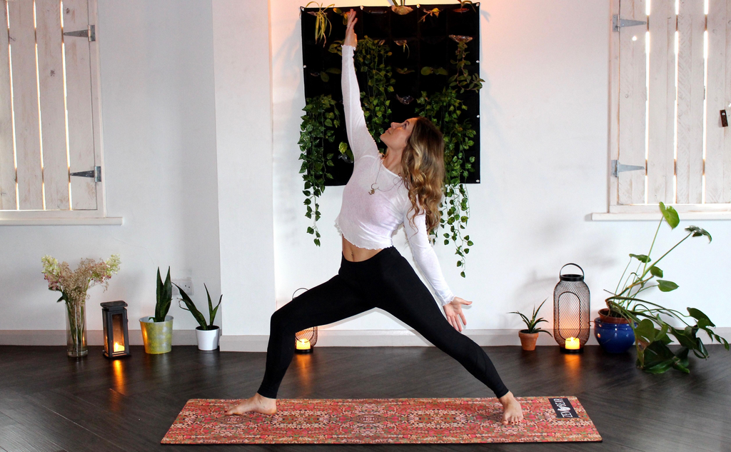 Woman doing yoga with plants and candles