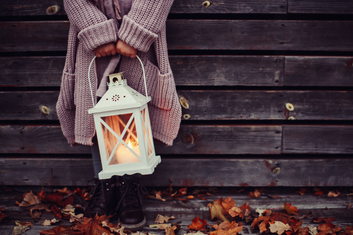 Woman in sweater holding a lantern fall season