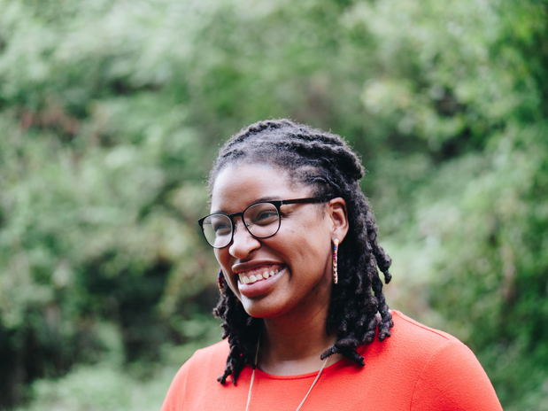 black woman with braided hair smiling by Unsplash