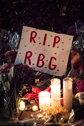 A poster saying R.I.P R.G.B laying on flowers and candles at Ruth Bader Ginsberg\'s memorial.