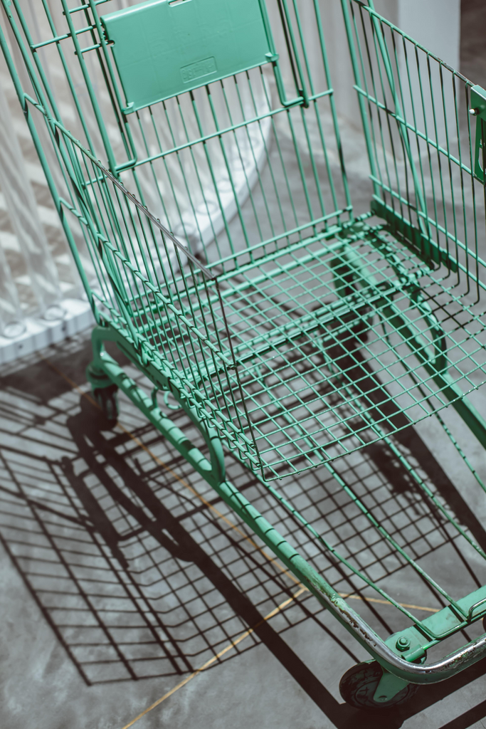 green metal shopping cart on white floor tiles