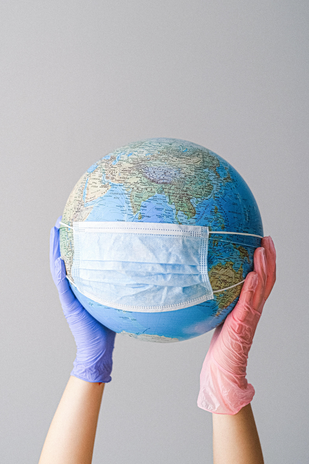 hands with latex gloves holding globe wearing a mask