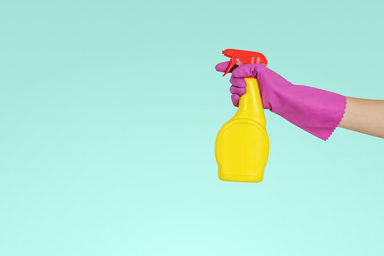 person holding yellow spray bottle and wearing pink gloves
