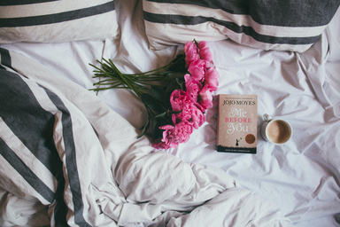 bouquet of pink flowers on a bed with a book