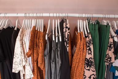 A clothing rack with various warm-toned outfits