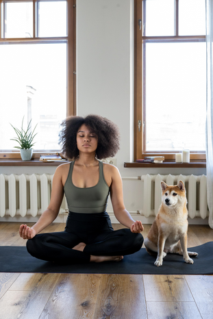 woman meditating with dog her by cotton bro