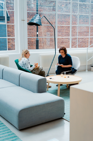 Two women sitting on a sofa at work by Unsplash