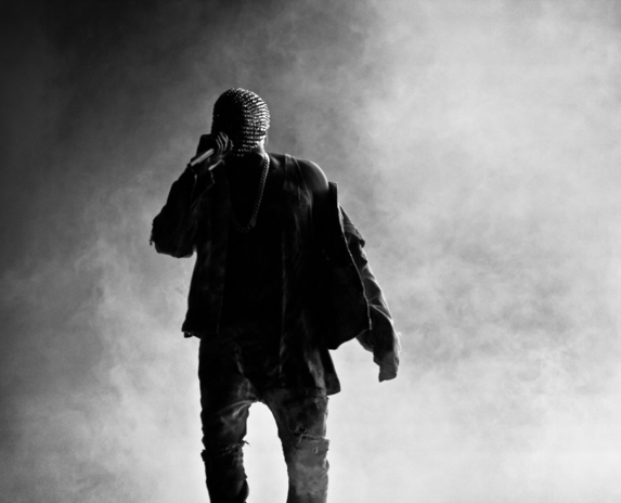 Kanye West performing on stage with face covering.