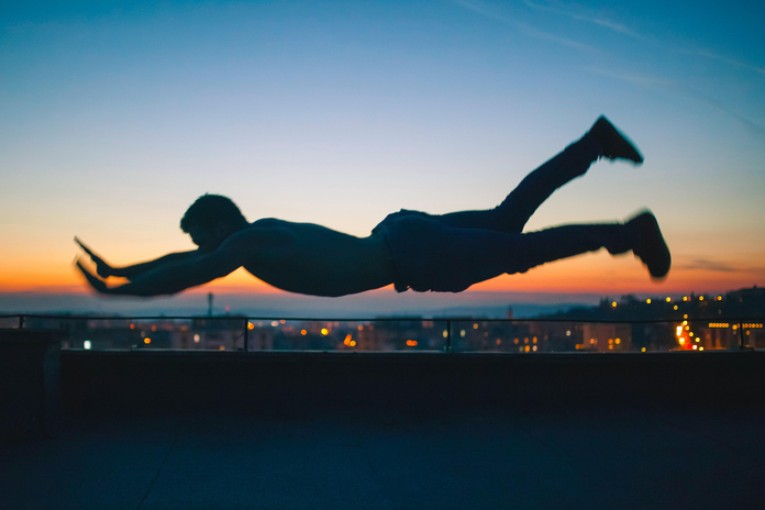 photo of a man hovering horizontally in front of a city scape