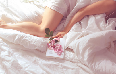 Woman laying in bed with a flower lying on a book
