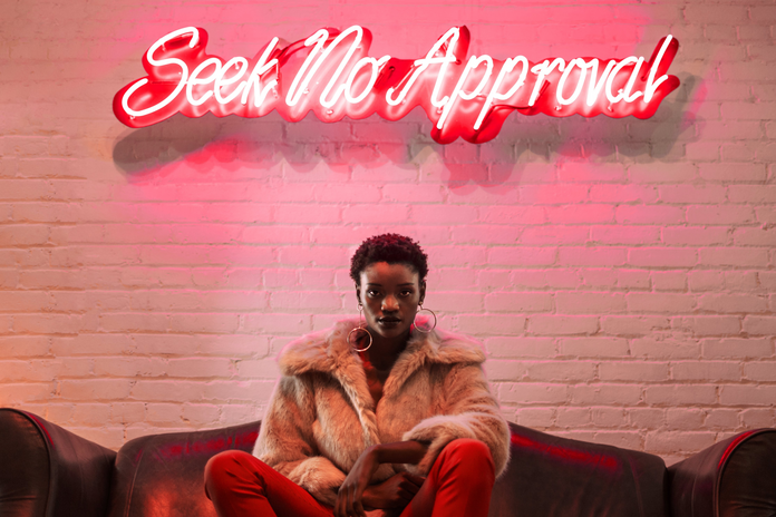 Seek No Approval. A neon light says it all as a model poses beneath.