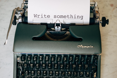 A page comes out of a typewriter that says \"Write something.\"