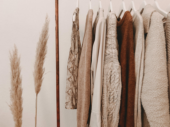 Neutral toned sweaters, long sleeved shirts and jackets on a rack