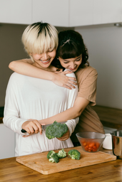 woman being hugged while cooking