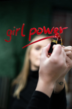 woman writing \"girl power\" with lipstick on a mirror