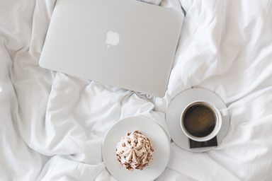 coffee, food and laptop spread on bed