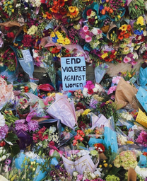 Flowers surrounding a sign which reads \'end violence against women\'