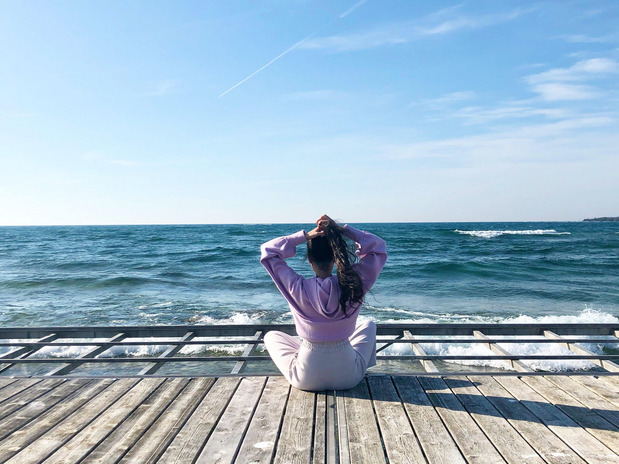 woman sitting on boardwalk facing ocean